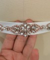 Bridal sash belt with a rose gold crystal and pearl appliqué that ties at the back in a bow