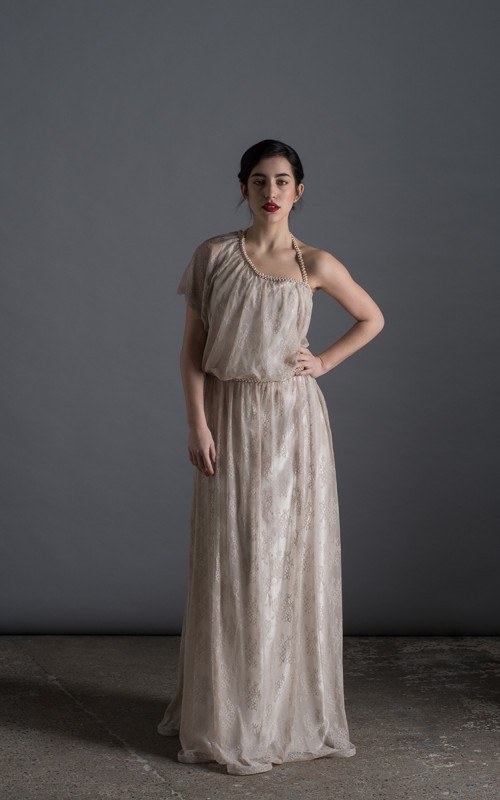 Bride wearing the Lucia one-sleeve vintage-inspired wedding dress in stone lace with pearl and crystal belt, handmade in London