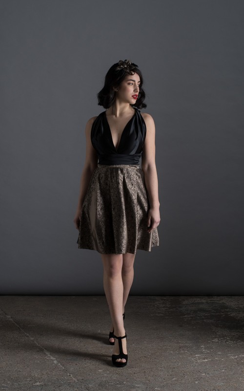 Valeria short halter cocktail dress with deep V-neck black satin bodice, open back and black and beige pleated jacquard skirt