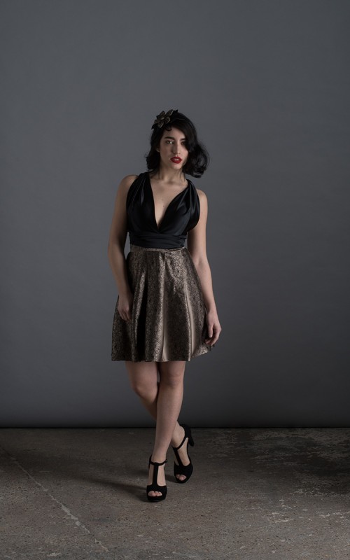 Valeria short halter cocktail dress with deep V-neck black satin bodice, open back and black and beige pleated jacquard skirt