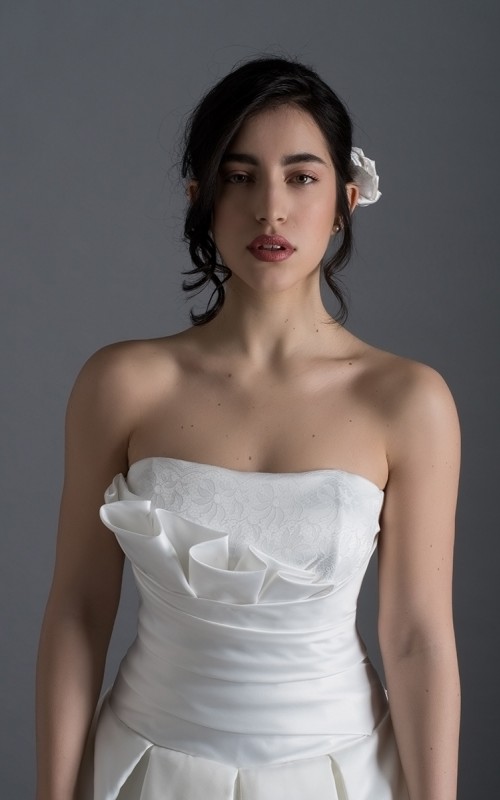 Bride wearing the Letizia strapless ball gown wedding dress in ivory duchess satin with corset lace-up back, handmade in London