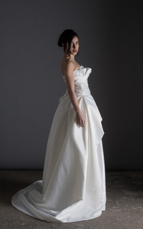 Bride wearing the Letizia strapless ball gown wedding dress in ivory duchess satin with corset lace-up back, handmade in London