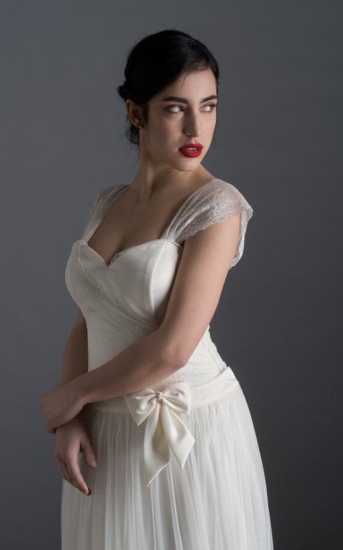 Bride wearing the Lia wedding dress in ivory satin with a detachable tulle overskirt and lace-trimmed train, handmade in London