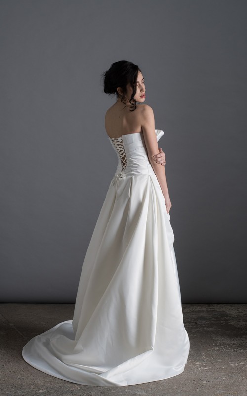 Bride wearing the Letizia strapless ball gown wedding dress in ivory duchess satin with corset lace-up back, handmade in London