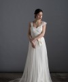 Bride wearing the Lia wedding dress in ivory satin with a detachable tulle overskirt and lace-trimmed train, handmade in London