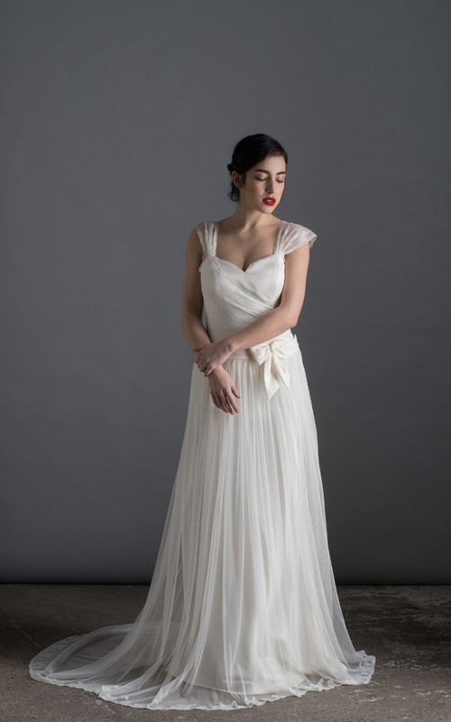 Bride wearing the Lia wedding dress in ivory satin with a detachable tulle overskirt and lace-trimmed train, handmade in London