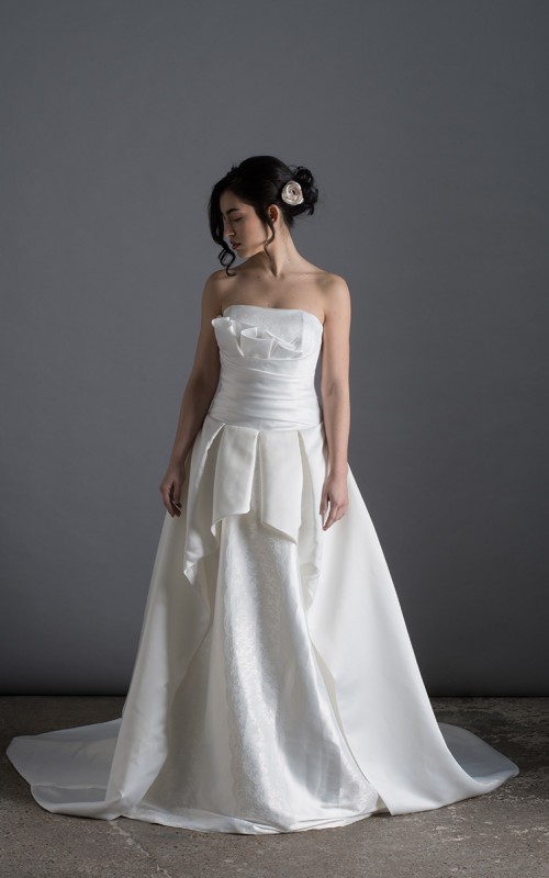 Bride wearing the Letizia strapless ball gown wedding dress in ivory duchess satin with corset lace-up back, handmade in London