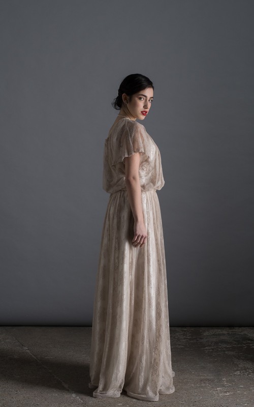 Bride wearing the Lucia one-sleeve vintage-inspired wedding dress in stone lace with pearl and crystal belt, handmade in London